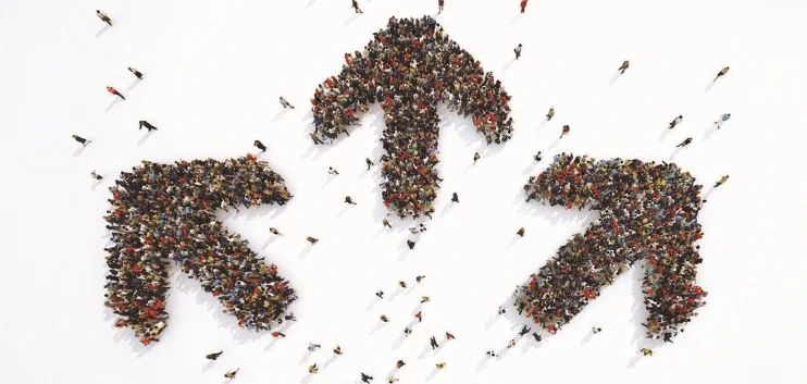 A large crowd of people standing in the shape of three arrows pointing in different directions against a white background.
