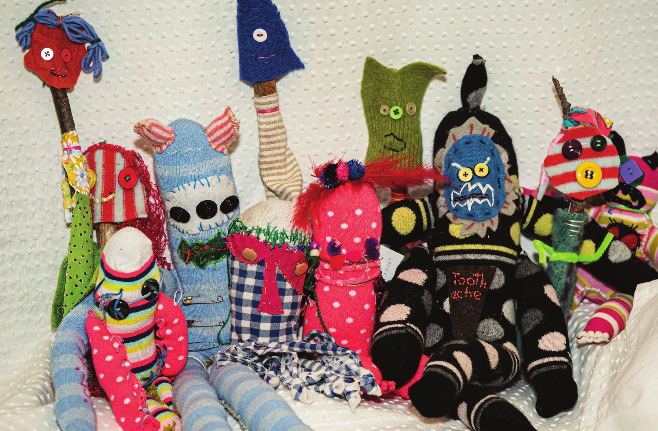 A group of handmade puppets crafted from colorful patterned socks, buttons, and fabric scraps.