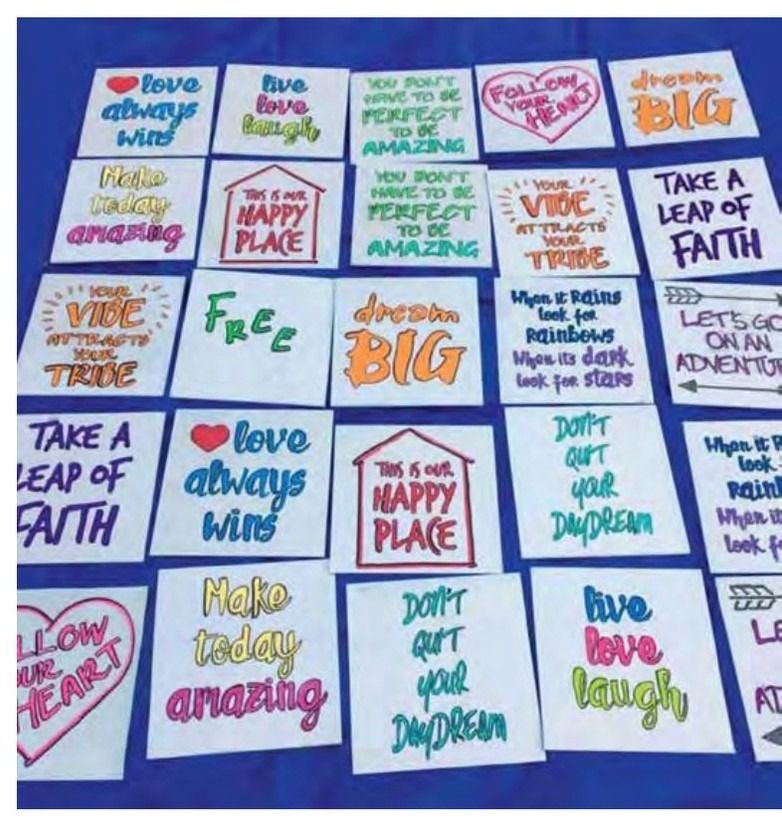 Multiple square cards arranged on a blue surface, each featuring a unique inspirational quote or phrase in colorful, stylized lettering.