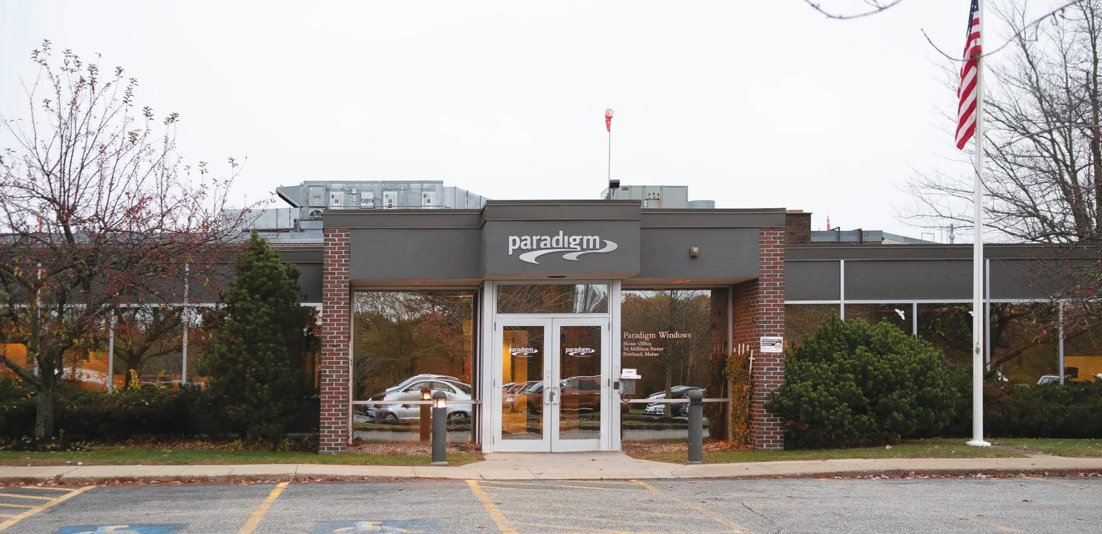 The Paradigm Windows home office building with a central glass entrance under an overcast sky.