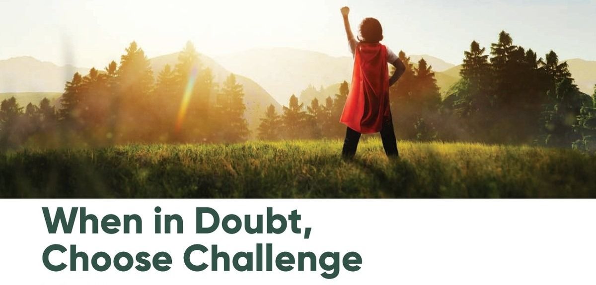 A child wearing a red cape stands in a field with a fist raised toward the sun, with the text When in Doubt, Choose Challenge below.