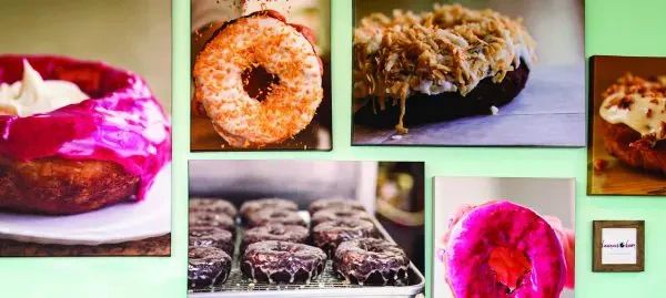 A gallery wall featuring several framed close-up photos of various glazed and topped doughnuts.